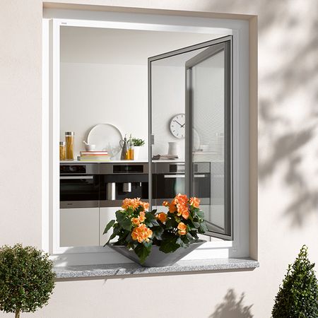 Geöffnetes Küchenfenster mit Fliegengitter-Drehrahmen und Blumenkasten mit orangefarbenen Blüten außen