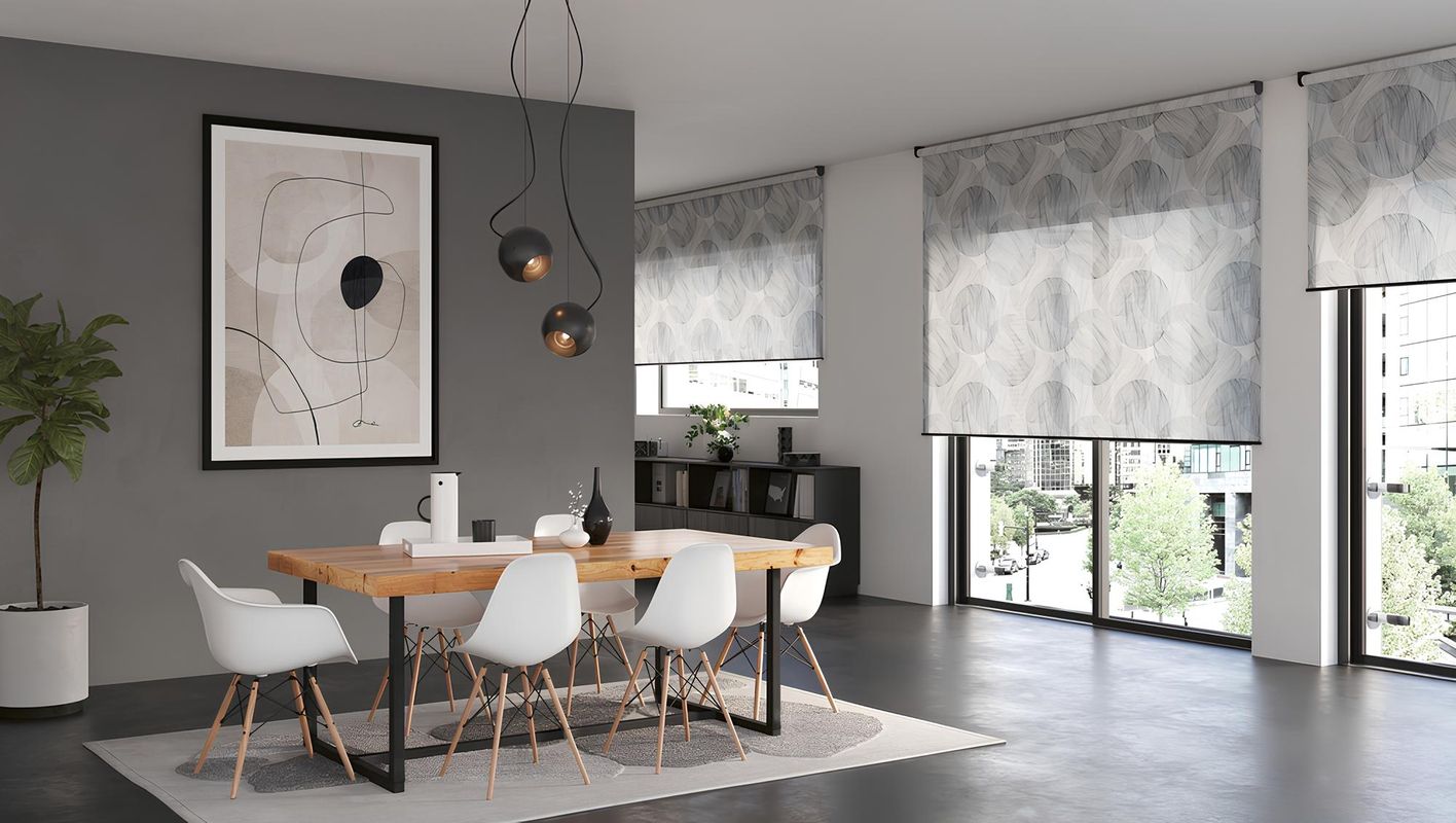 Modernes Esszimmer mit hellem Holztisch, weißen Stühlen im Skandi-Stil und großen Fenstern mit halbtransparenten Rollos im grauen Blattmuster.